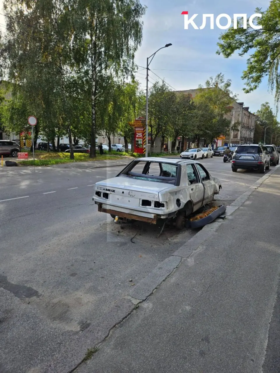 На улице Портовой в Калининграде остаётся повреждённый автомобиль без номеров; прохожие фиксируют разборку салона, вокруг — мусор, власти обещали сообщить сроки эвакуации.